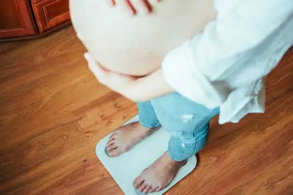 Image of woman weighing herself and experiencing weight gain through pregnancy Newport